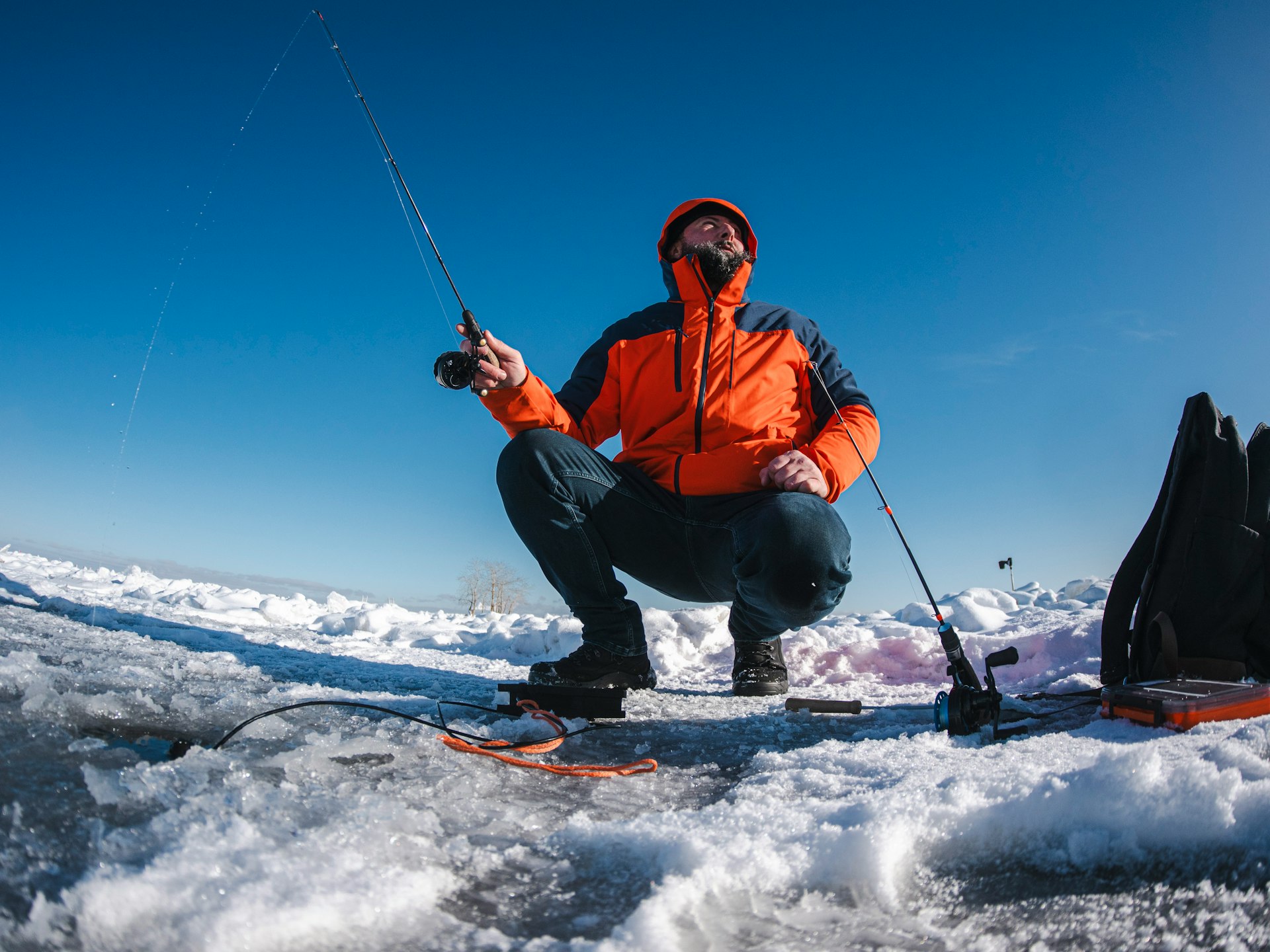 A person ice fishes on a frozen lake.